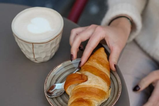 femme-prend-croissant-cafe-petit-dejeuner-honest-brussels