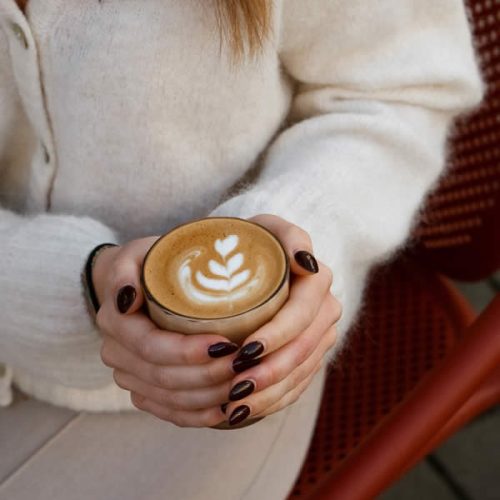 femme-tient-cafe-mains-lait-dessin-fleur-honest-brussels