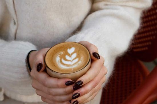 femme-tient-cafe-mains-lait-dessin-fleur-honest-brussels